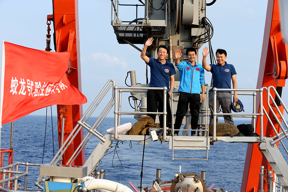 5月6日，深潜归来的中国海洋大学副教授毕乃双、实习潜航员刘晓辉和潜航员唐嘉陵（从左至右）挥手致意。